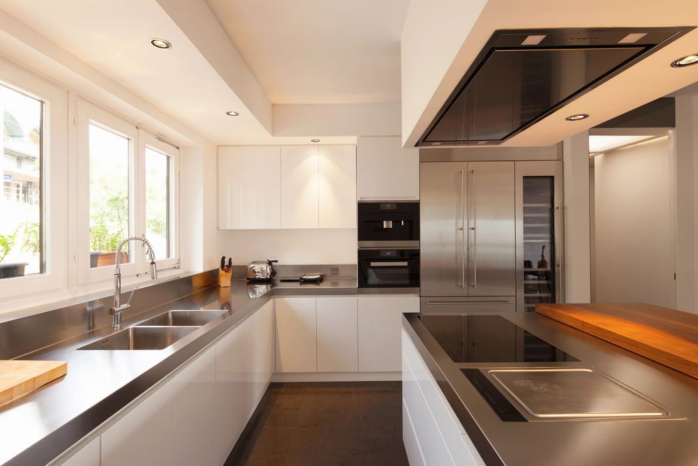 A kitchen with stainless steel counter tops and white cabinets