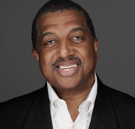 A man and a woman are sitting on a dock overlooking a lake.