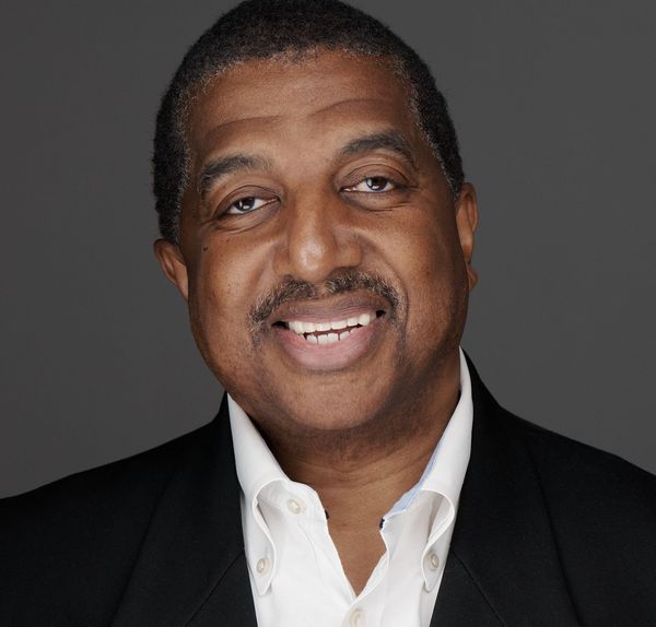 A man is holding a dog in his arms and the dog is wearing a sweater.