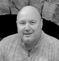 A bald man is smiling in a black and white photo.