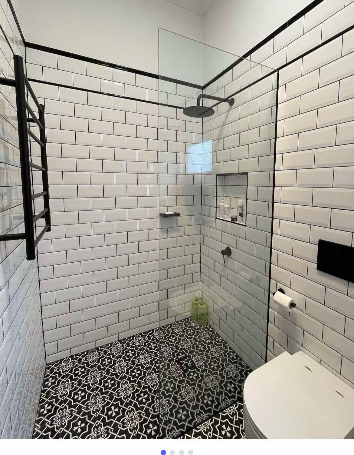 Bathroom with white subway tile walls, black and white patterned floor, and a glass shower.
