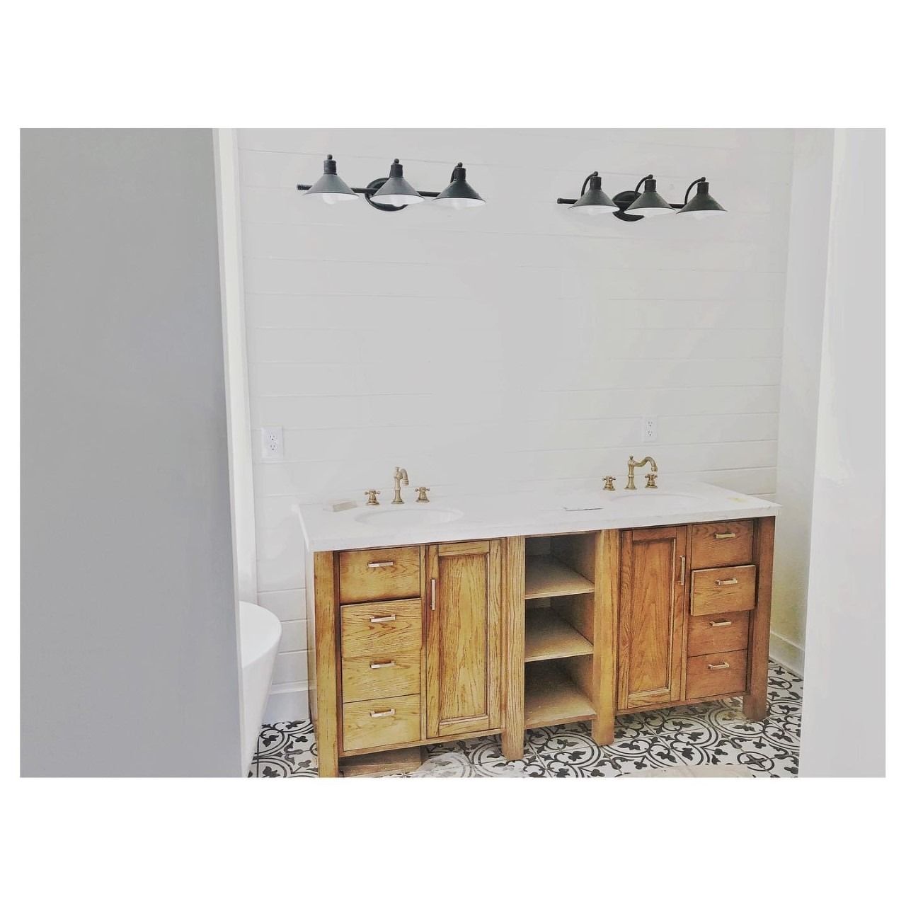 Bathroom with wooden double vanity, marble countertop, and black and white patterned floor.