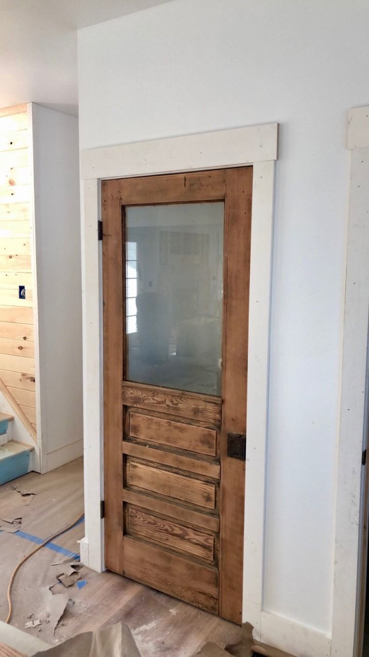 Wooden door with frosted glass panel and paneling, set in white trim.