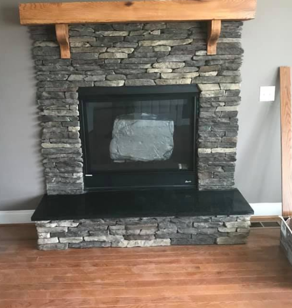 Stone fireplace with black granite hearth and wooden mantel.