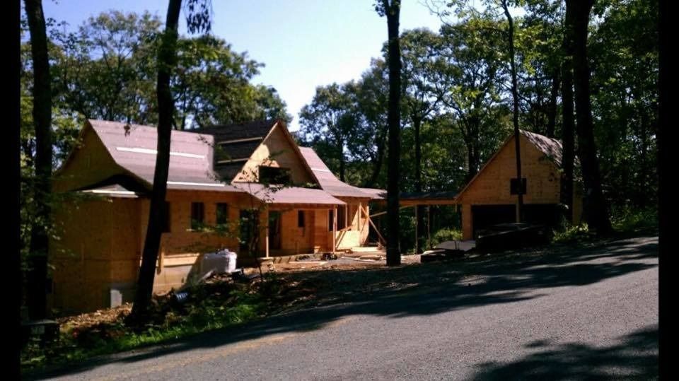 House under construction with attached garage surrounded by trees on a sunny day.