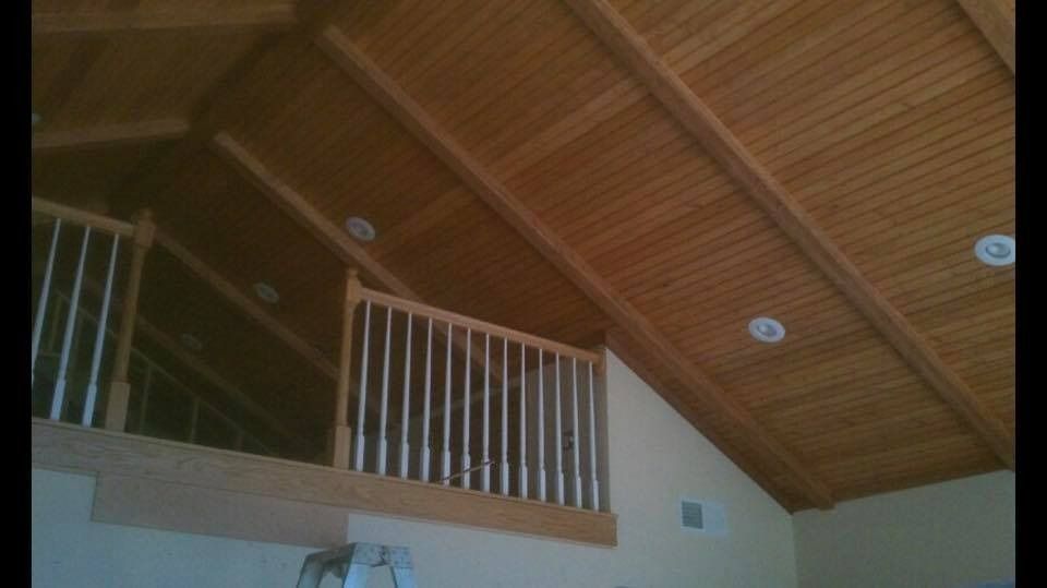 Wooden slatted ceiling and balcony with white railing.
