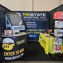 A roofing booth with a sign that says `` we got you covered '' and a table.
