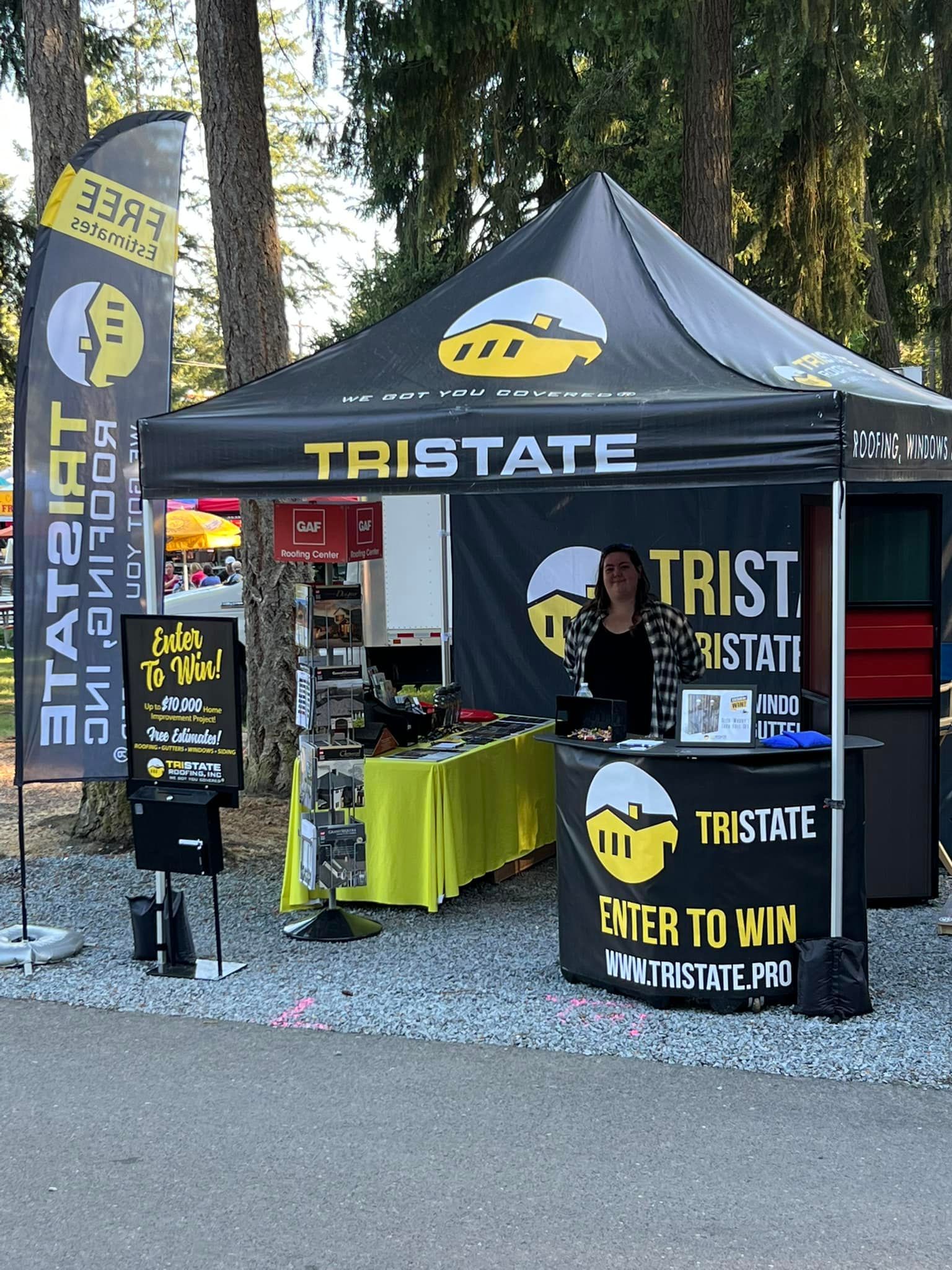 A woman is standing in front of a tent that says tristate on it.