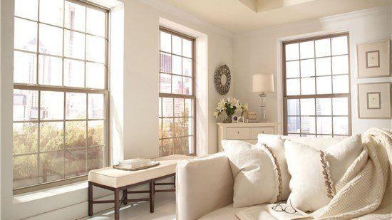 A living room with a couch , bench , and lots of windows.