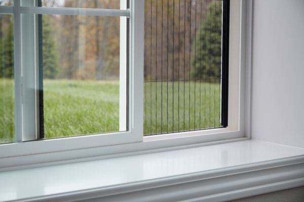 A close up of a window with a view of a lush green field.