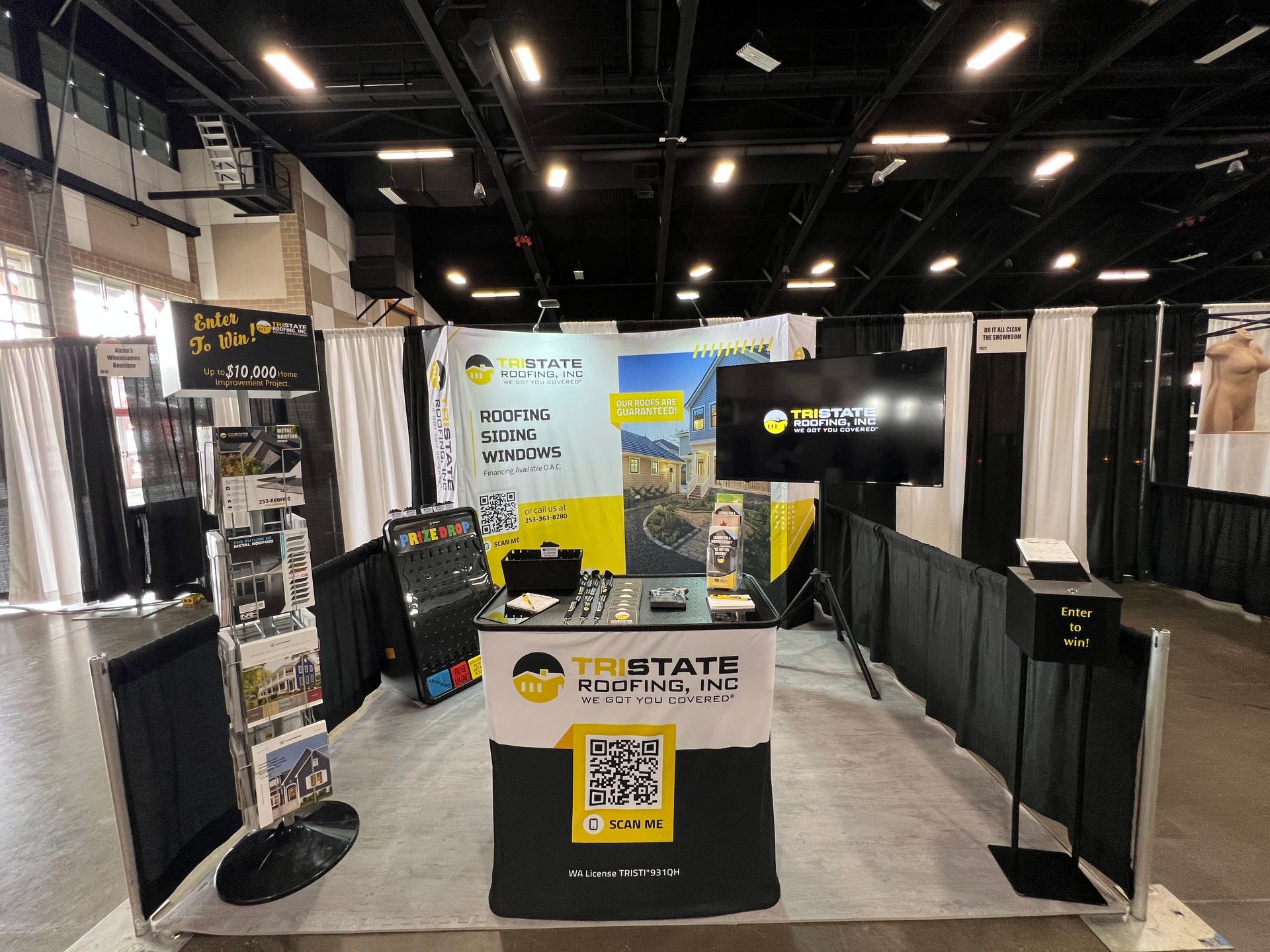 A booth with a table and a tv in a large room.