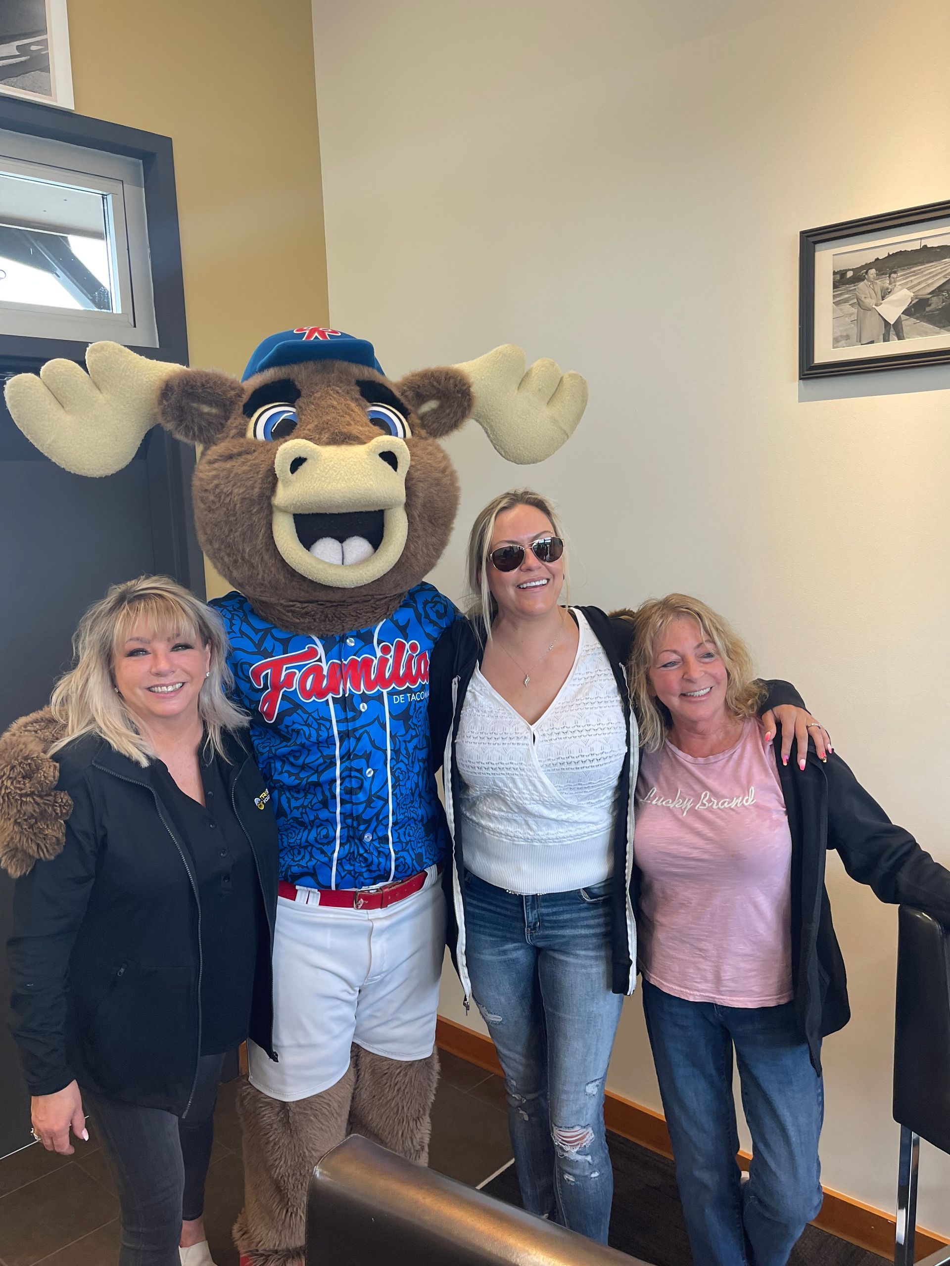 Three women are posing for a picture with a moose mascot.