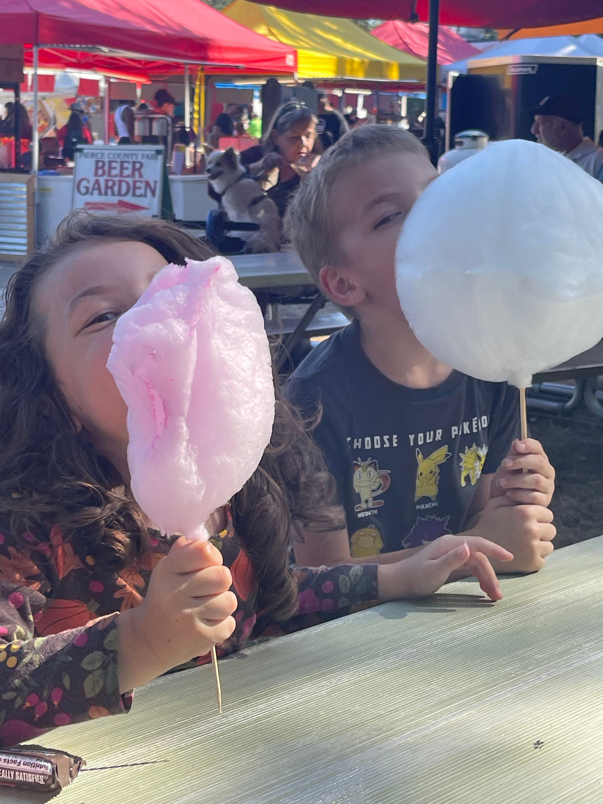 A boy and a girl are eating cotton candy at a beer garden