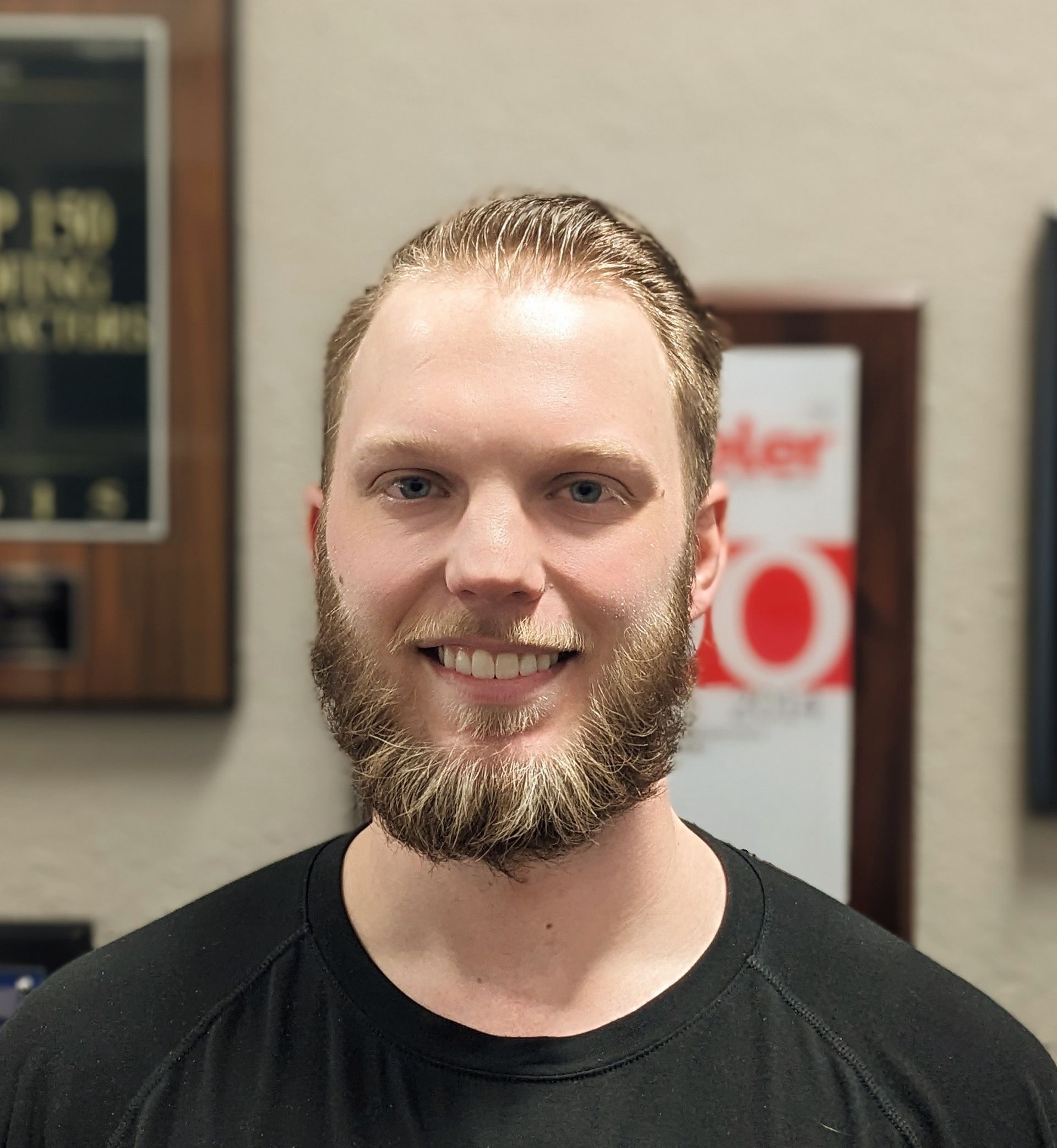 A man with a beard wearing a black shirt is smiling