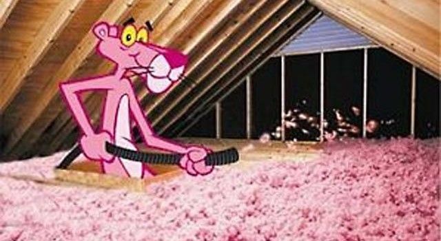 A pink panther is standing in an attic holding a vacuum cleaner.