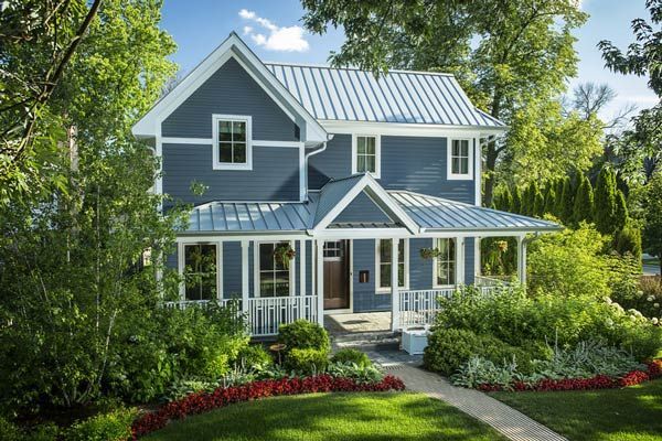 A blue house with a white trim and a metal roof