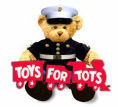 A teddy bear in a marine uniform is holding a sign that says `` toys for tots ''.