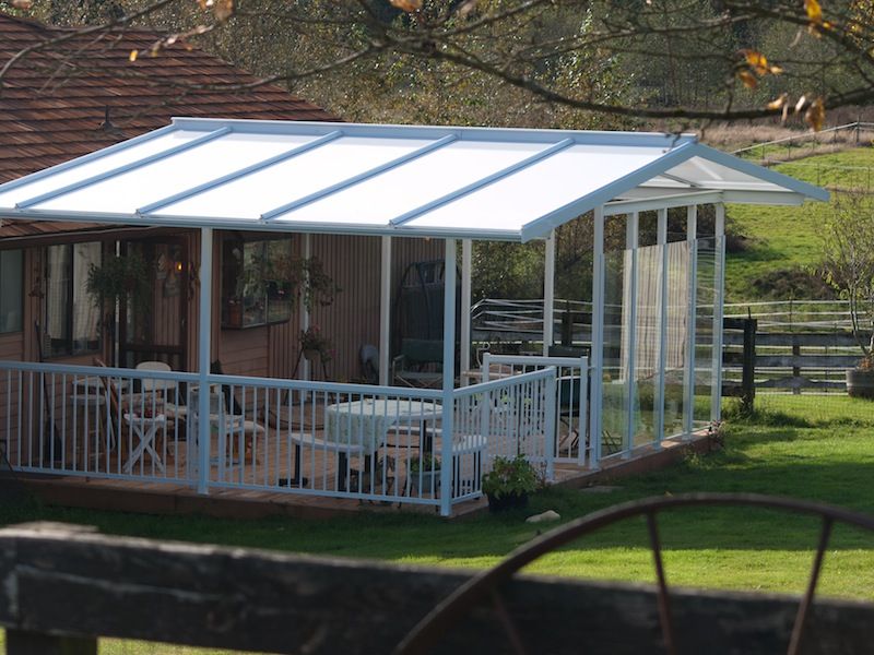 A covered porch with a table and chairs in front of a house