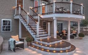 A deck with stairs leading up to it and a house in the background.