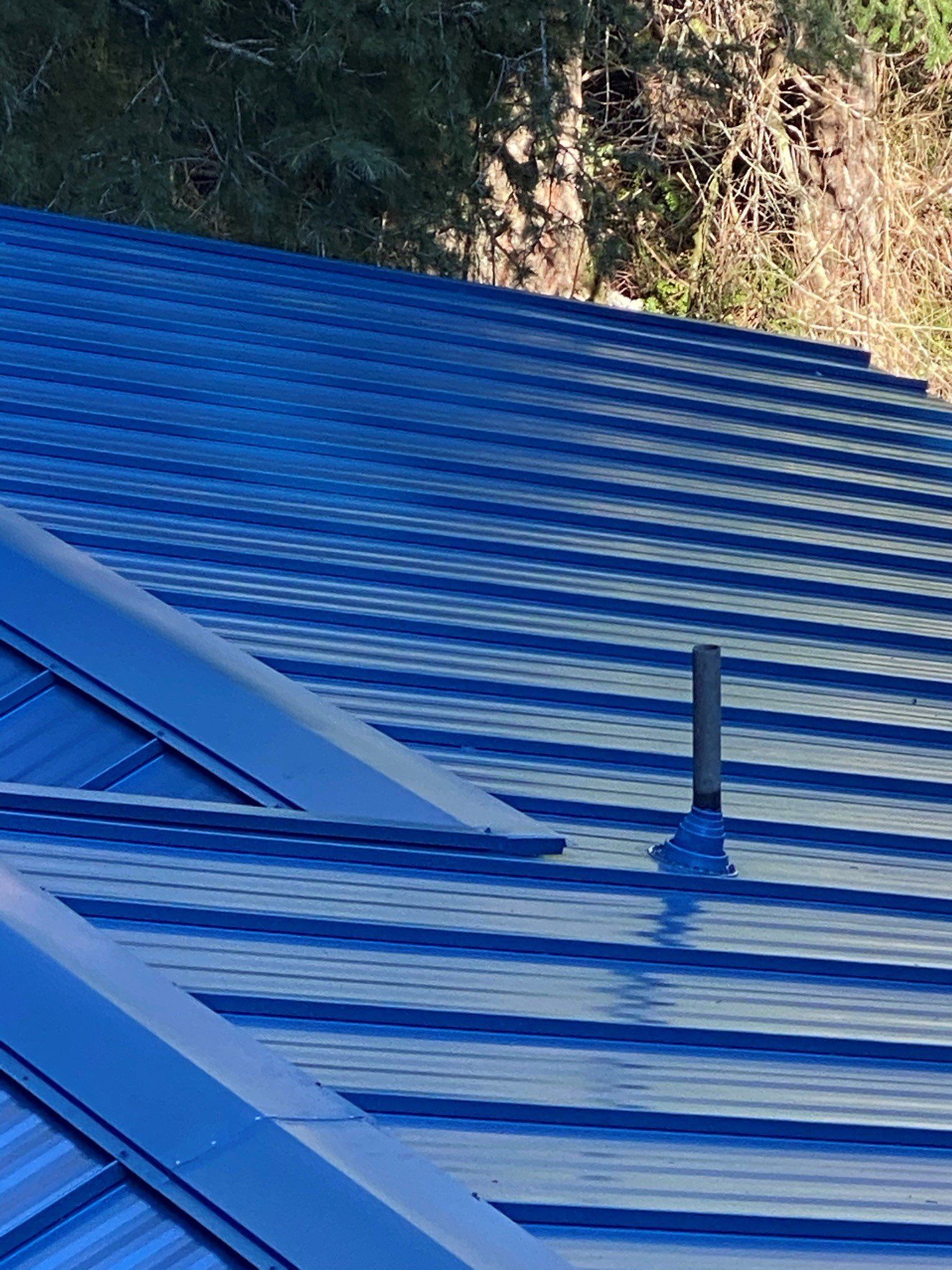 A close up of a blue roof with a chimney on it.