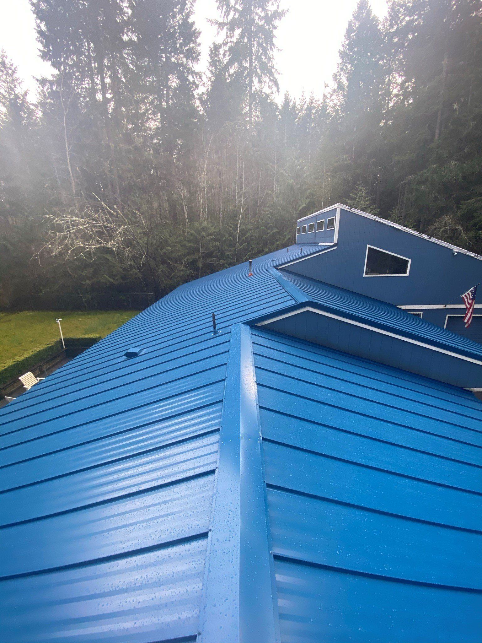 A blue roof with a window and trees in the background