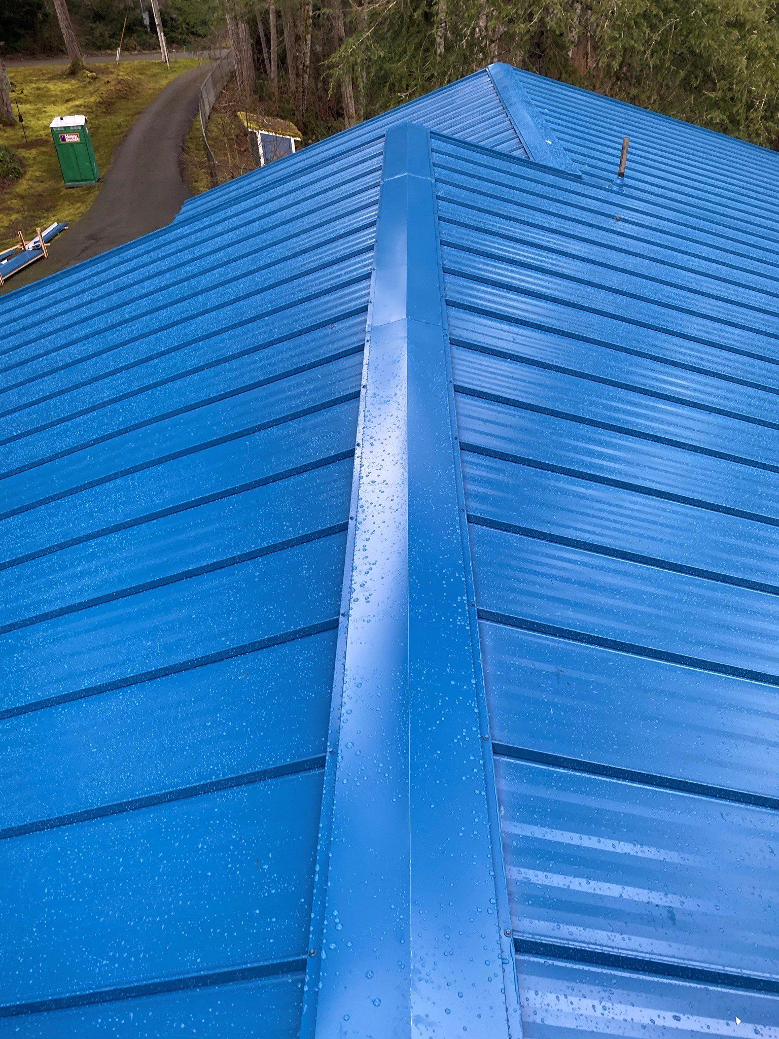 A blue metal roof with a gutter on the side of it.
