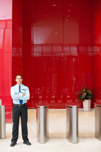 Security guard standing in lobby near turnstiles.