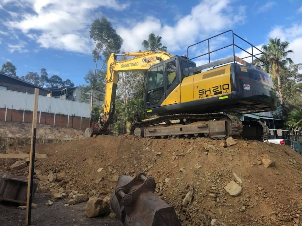 A large yellow excavator is sitting on top of a pile of dirt.