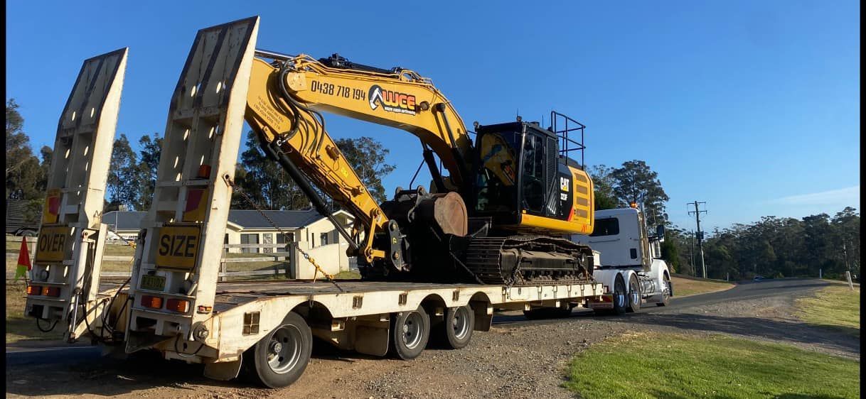 A yellow excavator is sitting on top of a trailer.