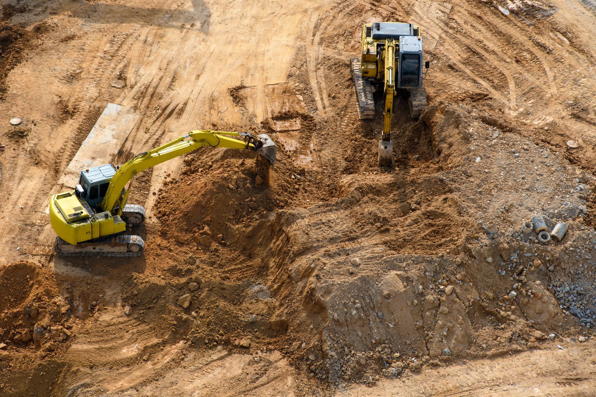 A yellow excavator is digging a hole in the dirt on a construction site.
