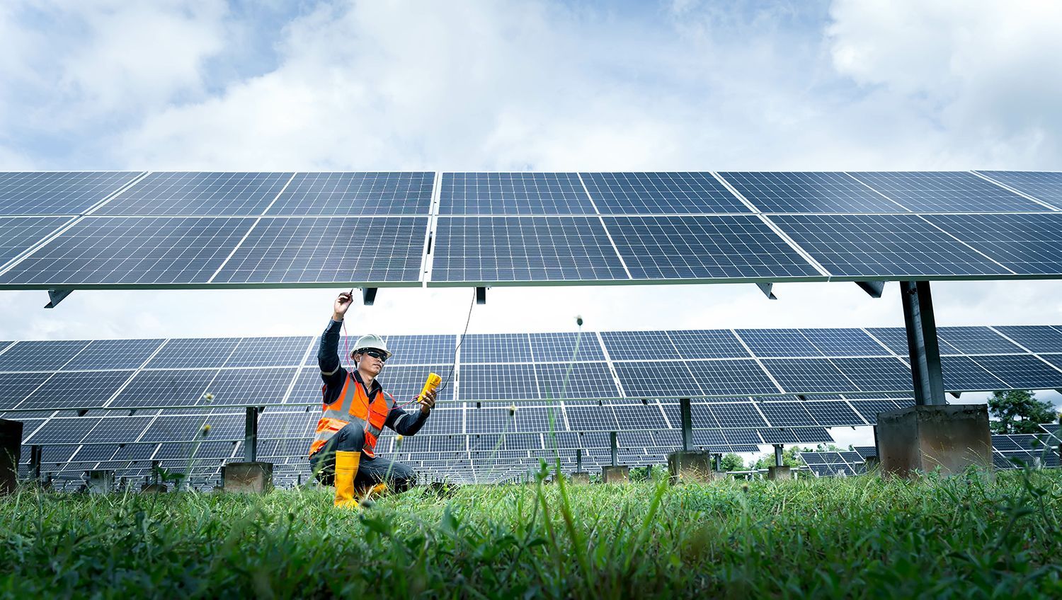 A man is working on a solar panel in a field.