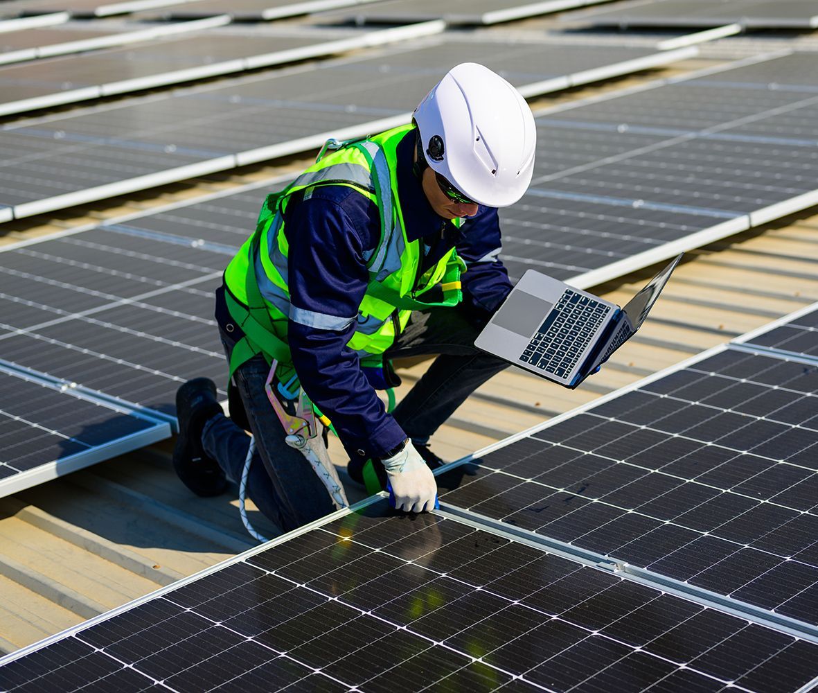 A man is working on a solar panel with a laptop.