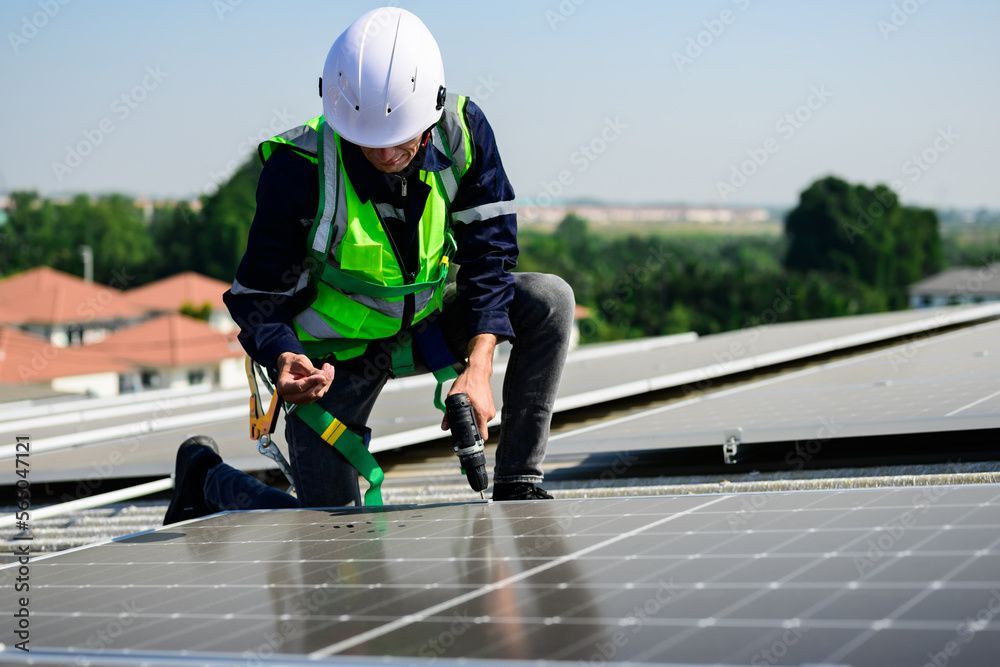 A man is installing solar panels on the roof of a building.