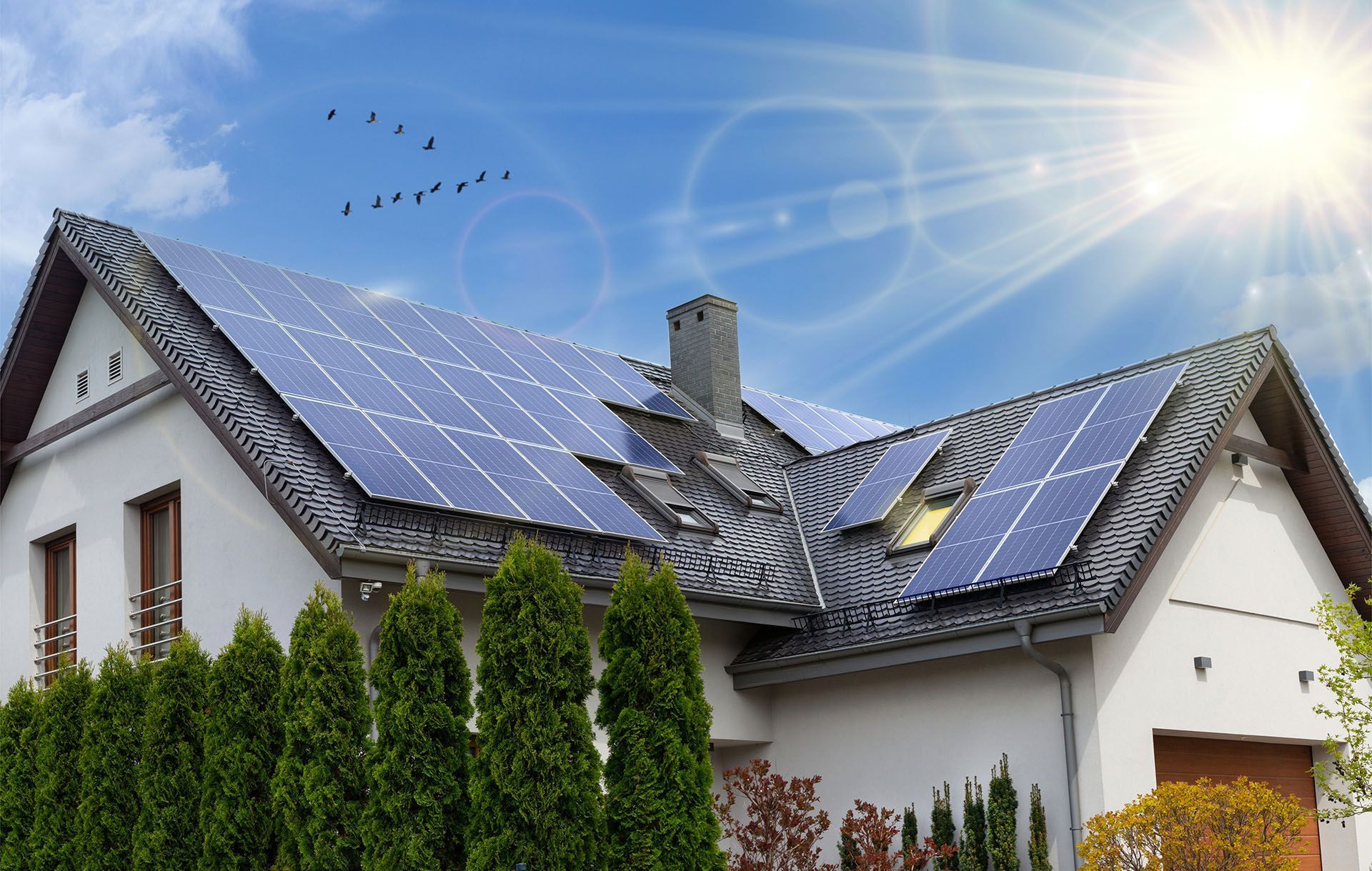 A white house with solar panels on the roof.