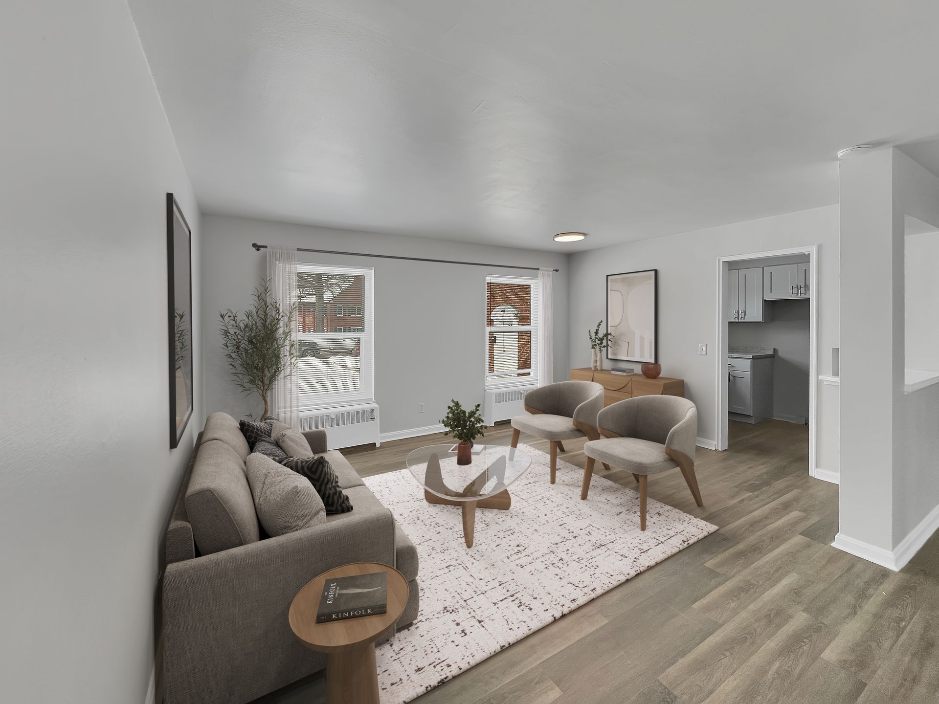 Living room with gray walls, sofa, two chairs, rug, and windows.