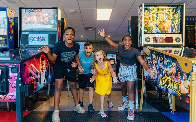 Group of kids smiling and playing arcade games at Pinball Garage in Hamilton, Ohio.