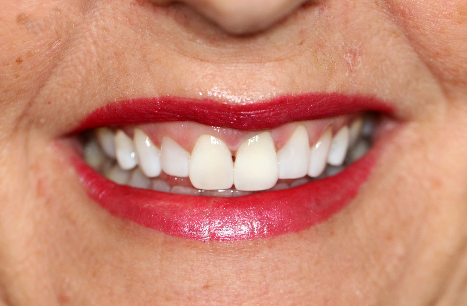 A close up of a woman 's mouth with red lipstick and white teeth.