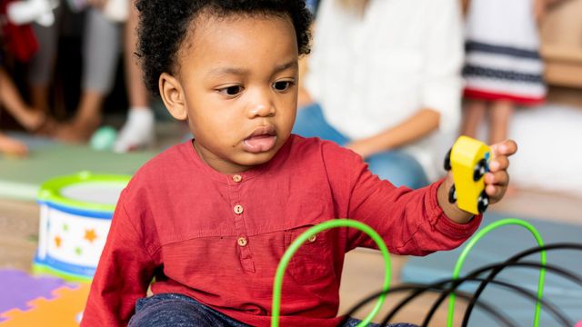 A young boy is sitting on the floor playing with a toy car.