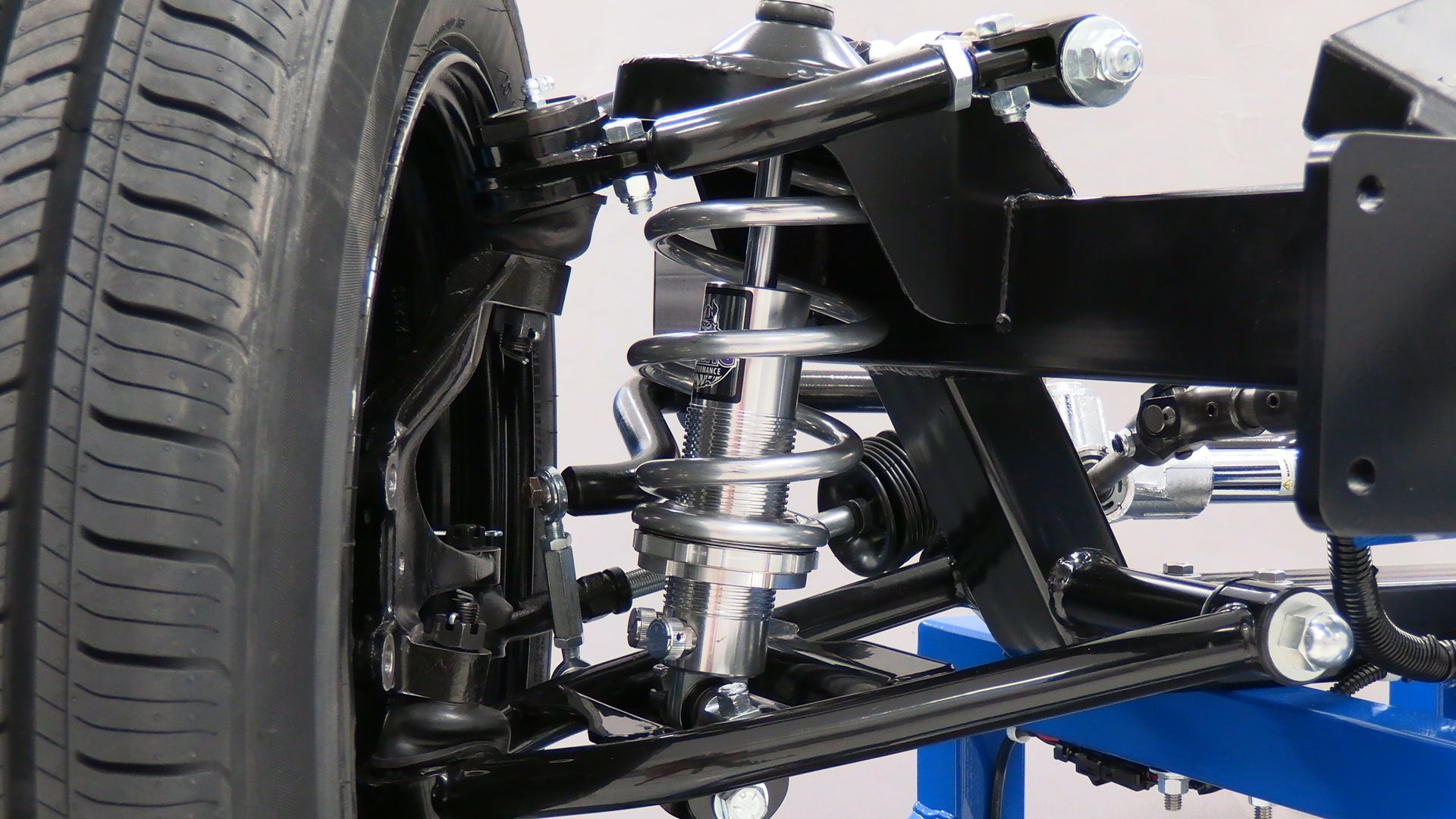 A close up of a car suspension with a tire in the background.