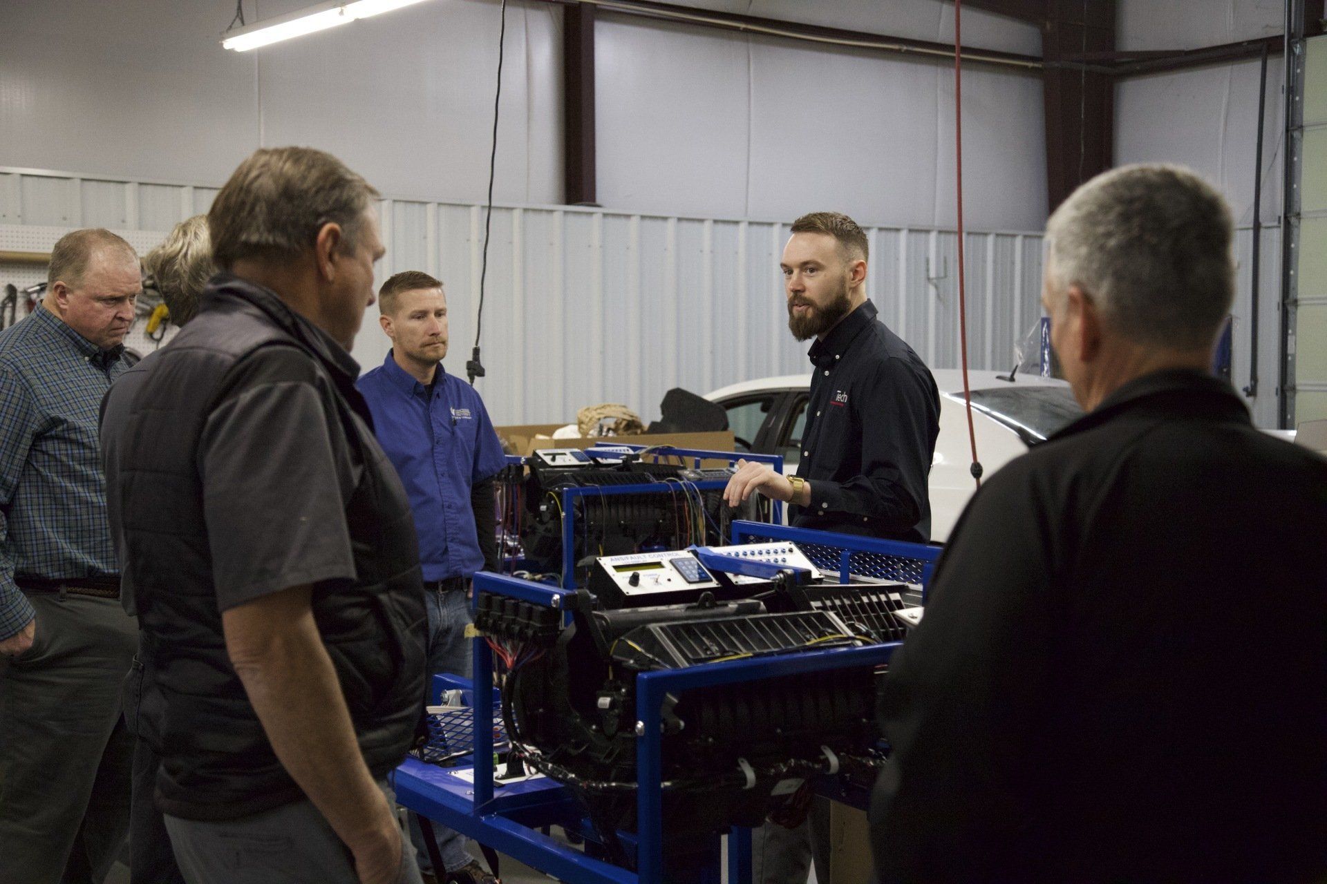 A group of men are standing around a machine in a garage.