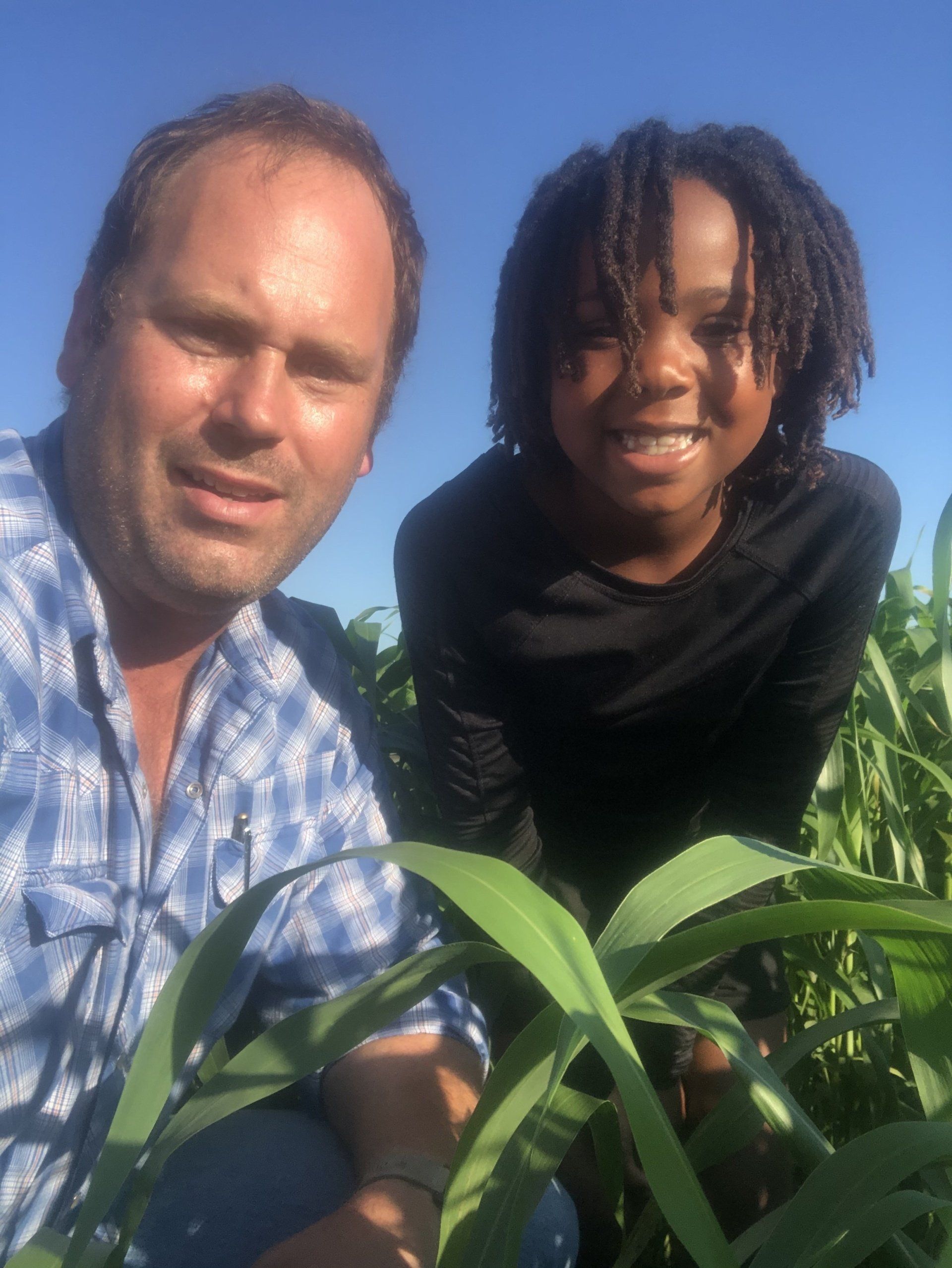 A man and a girl are posing for a picture in a corn field