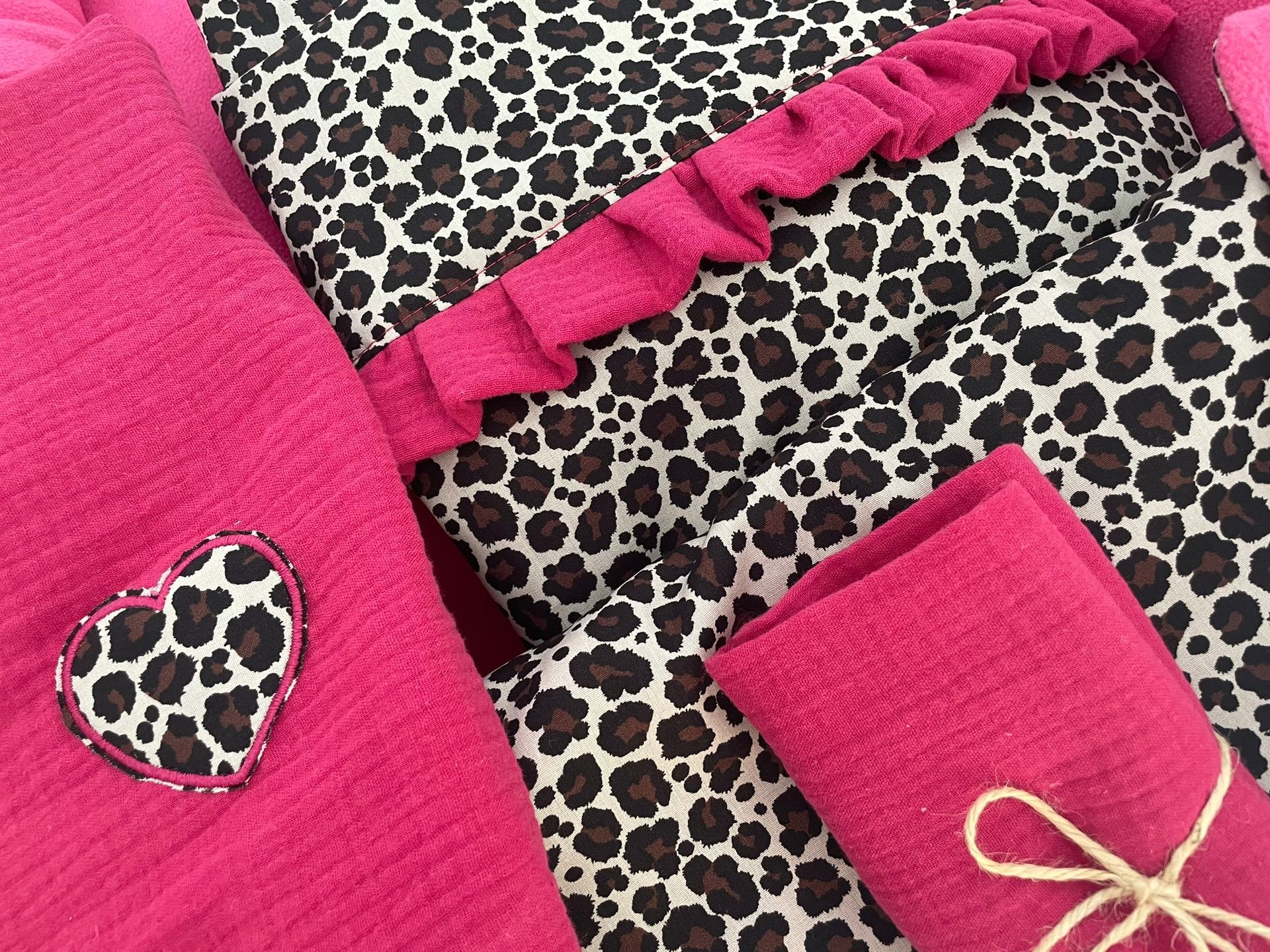 Roze hondenmand met kussens met luipaardprint en een klein ingepakt roze cadeautje erin.