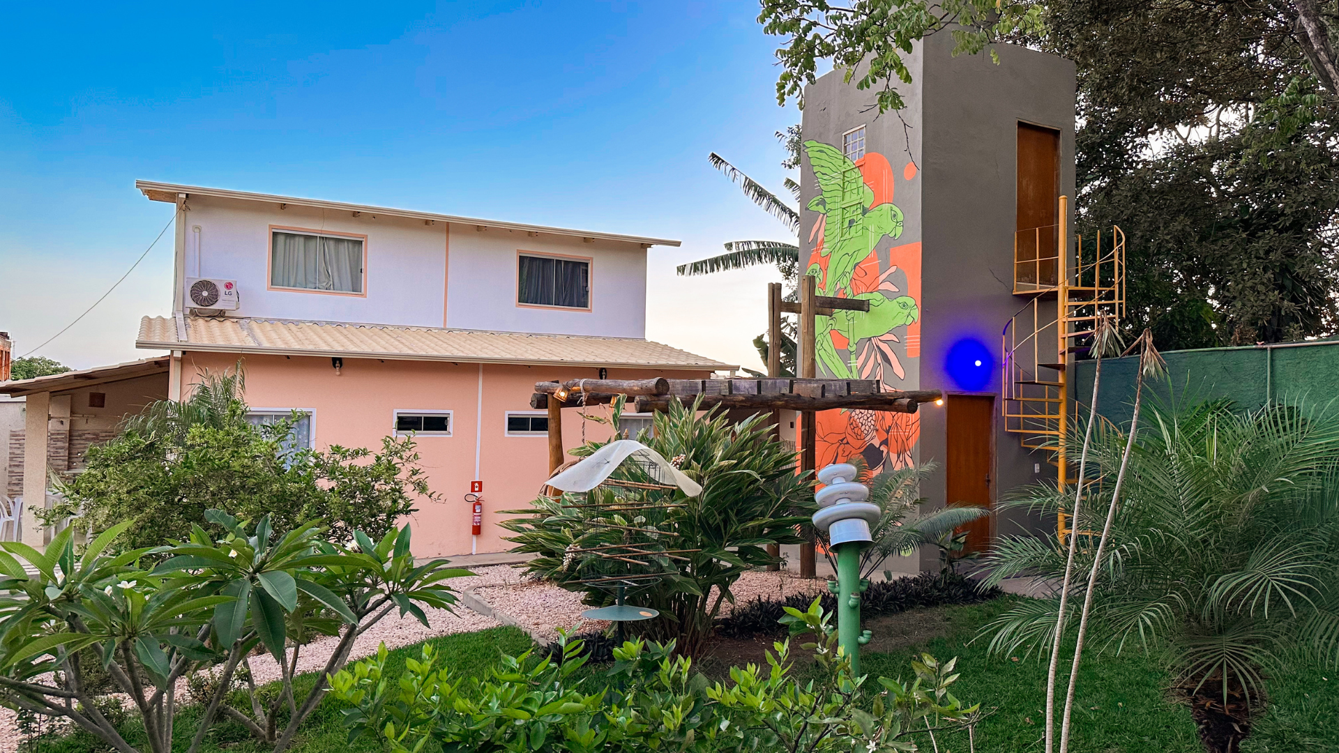 Prédio com mural colorido, escada em espiral e jardim.