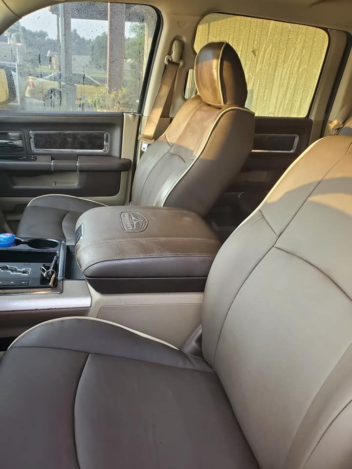 Interior view of a truck with tan and gray leather seats, center console, and window.