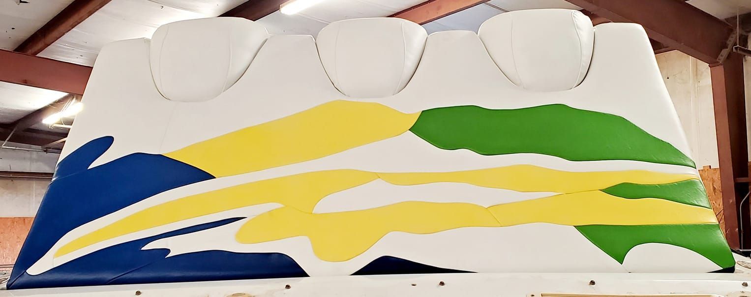 White object with blue, yellow, and green abstract design, possibly a boat, in a building.