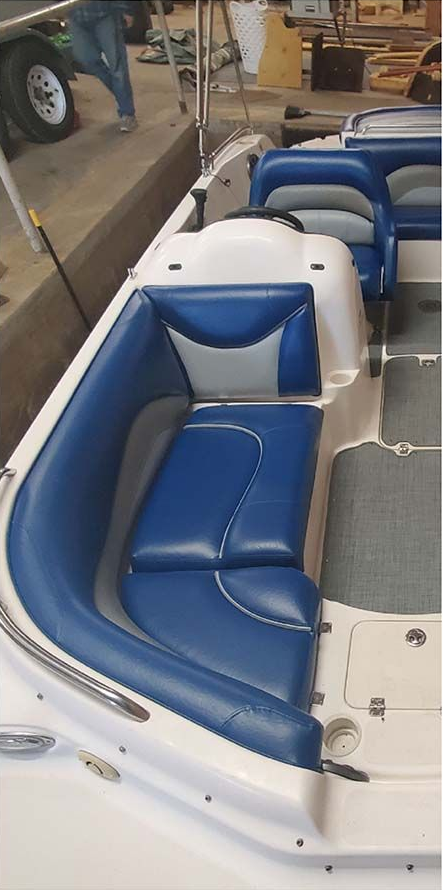 Blue and gray boat seating. White boat interior. Boat is in a workshop.