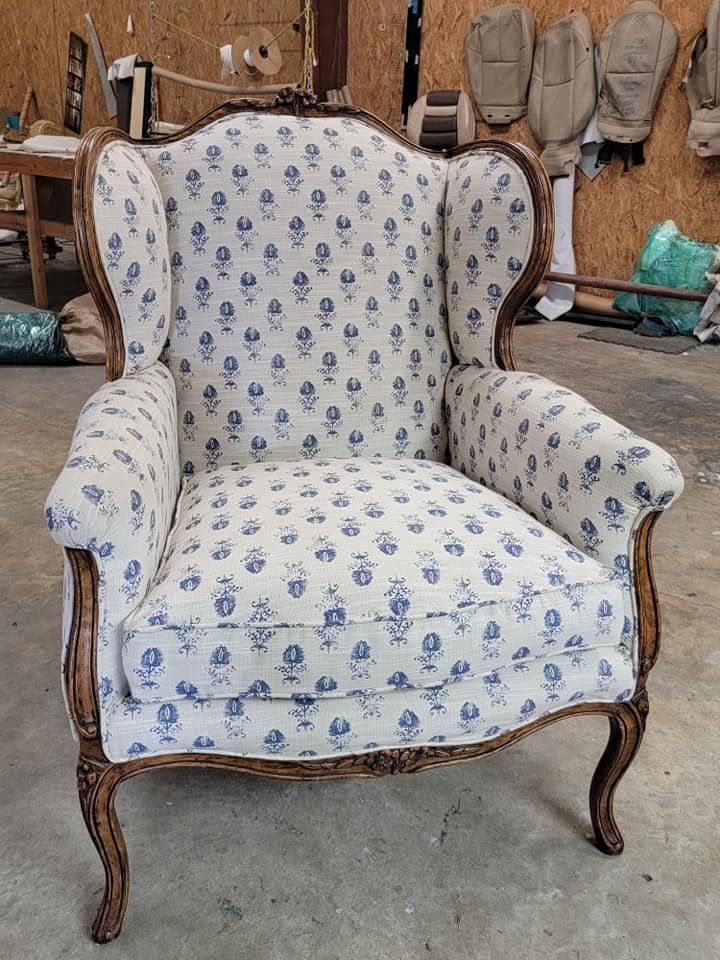 Wingback armchair with blue floral pattern on cream fabric, wooden frame.