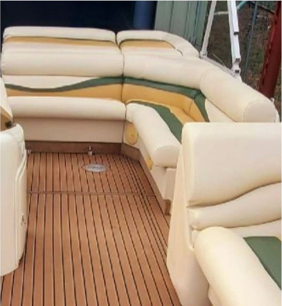Pontoon boat interior with cream and green seating, wooden flooring.