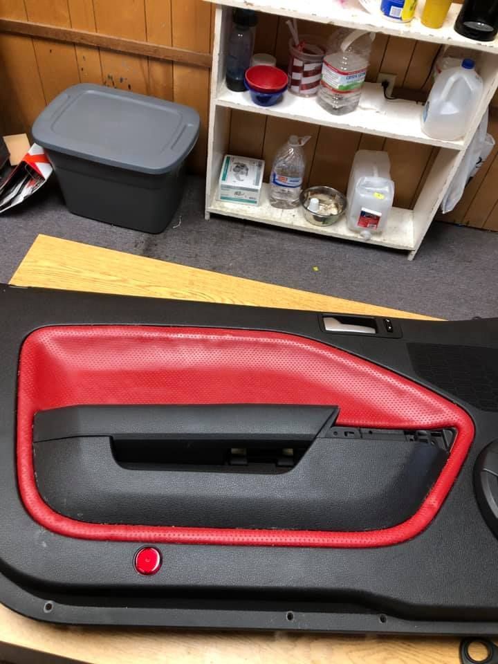 Red and black car door panel, partially disassembled, with red leather trim.