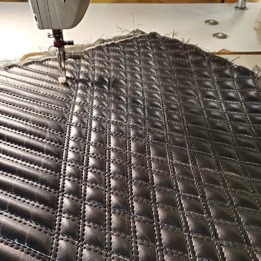 Sewing machine stitching quilted dark gray leather.